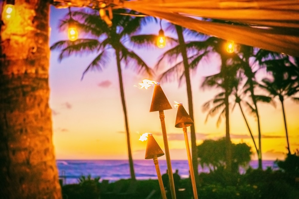 hawaii luau party with fire torches at sunset